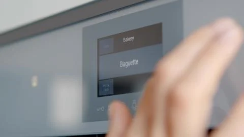 Close up of woman touching sensor button on electric oven in kitchen Photos