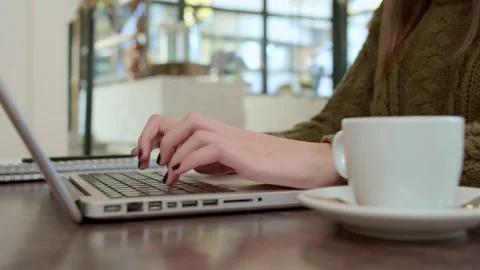 Close up of woman typing on a laptop while sitting in a cafe. Stock Footage 141366765