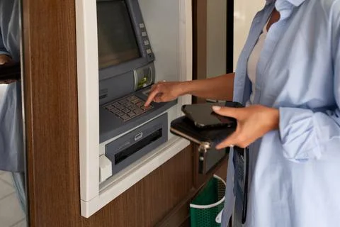 Close-up of a woman using an ATM and holding a wallet Stock Photos