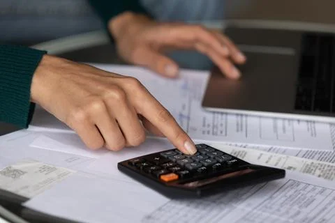 Close up woman using calculator, checking domestic bills, finances Fotos de archivo