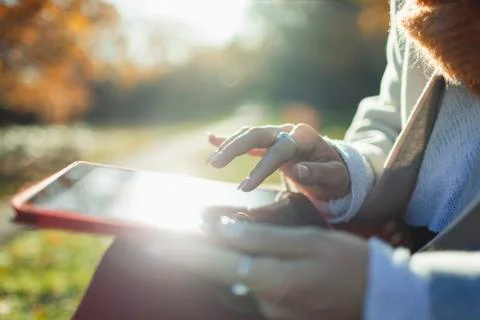 Close up woman using digital tablet in sunny autumn park Stock Photos