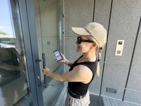 Close up of woman using intercom at building entrance. Stock Photos