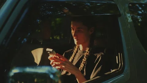 Close-up of a woman using a mobile phone inside a vehicle with warm... Stock Footage 341613100