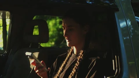 Close-up of a woman using a mobile phone inside a vehicle with warm... Vídeos de archivo 341613107