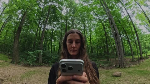 Close-up of a woman using a smartphone on a forest path... 스톡 동영상 339101254