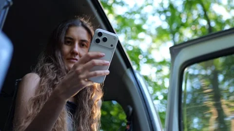 Close-up of a woman using a smartphone inside a car, engaging... Video stock 340290926