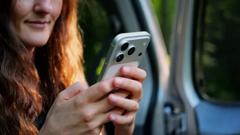 Close-up of a woman using a smartphone inside a car, browsing social... Stockbeeldmateriaal 340290959