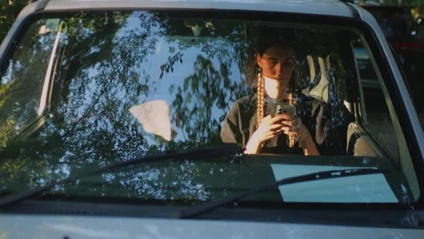 Close-up of a woman using a smartphone inside a parked car behind... Stock Footage 341613098