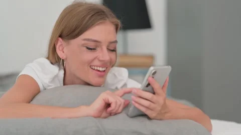 Close up of Woman Using Smartphone while Lying on Stomach in Bed Stock Footage 287901201