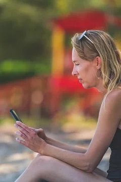 Close up Woman using smartphone while vacationing on beach 写真素材