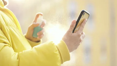 Close-up. Woman using spray on the mobile phone. Stock Footage 129880529