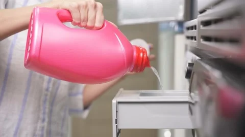 Close-up of a woman without a face, she pours a laundry conditioner into a Stock Footage 237912258