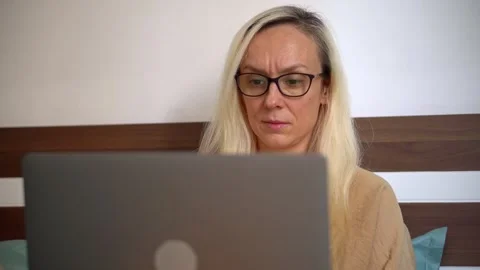 Close-up of a woman working on a laptop while sitting on a bed Vidéo 340979324