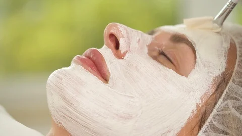 A close up of woman's face covered with white mask. A hand with a brush  Stock Footage 96188587