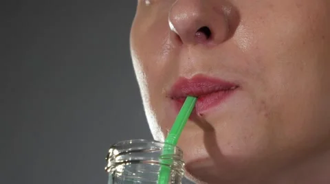 A close up of a woman's face sipping from a bottle, with a straw Stock Footage 62472802