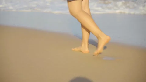  Close-up of a woman's feet walking along the seashore at sunset Vidéo 320507909