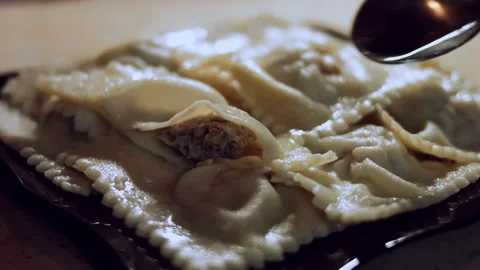 Close-up woman's hand adding melted butter to cooked ravioli. Preparing ravioli Stock Footage 144834422