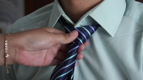 Close up of a woman's hand adjusting and fixing a blue striped necktie on a man Video stock 337760912