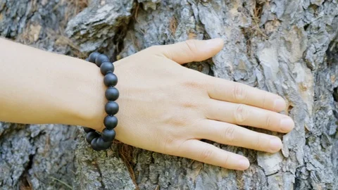 Close-up of a woman's hand with a bracelet, which is carefully stroking the tree Stock Footage 128147198