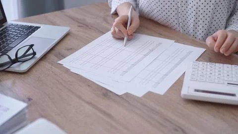 Close-up of a woman's hand checking financial paper while sitting and using Stock-Fotos