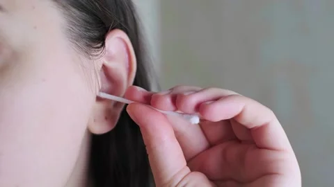 Close-up of a woman's hand cleaning her ear with a cotton swab, personal care pr Stock Footage 296575731