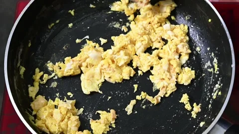 Close-up of woman's hand cooking egg food in frying pan over the gas stove Stock Footage 203476390