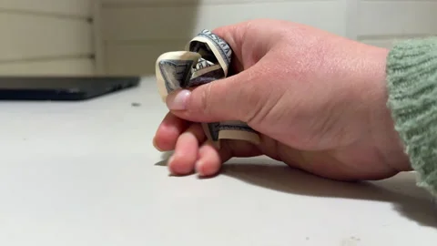 Close-up of a woman's hand crumpling a dollar bill against a gray wall Stock Footage 306277157