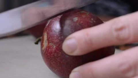 Close-up of a woman's hand cuts a red passionfruit with a knife in the middle Stock Footage 151595304