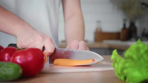Close-up of a woman's hand cutting a carrot with a kitchen knife. Stock Footage 195993045