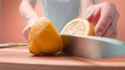 Close-up of a woman's hand cutting a lemon in half in 4K. Stock Footage 141308916
