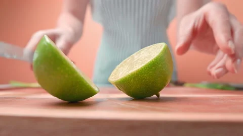 Close-up of a woman's hand cutting a lime in half in 4K. Stock Footage 141309365