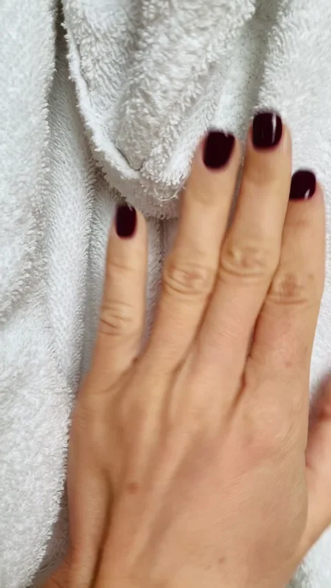 Close-up of a woman's hand with dark red manicure gently holding a bathrobe Stock Footage 303271082