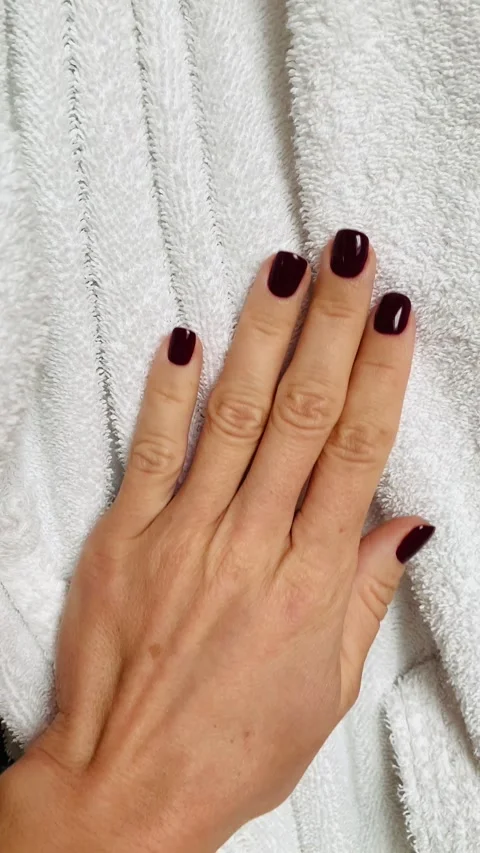Close-up of a woman's hand with dark red manicure gently holding a bathrobe Stock Footage 303271087