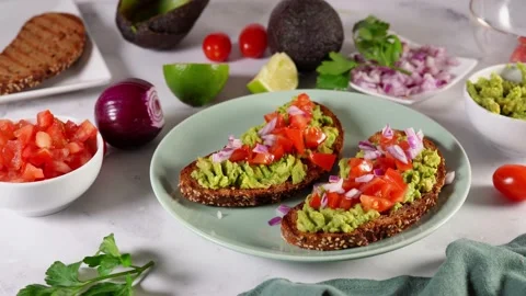 Close up of woman's hand decorating healthy vegan avocado toasts Stock Footage 136872051