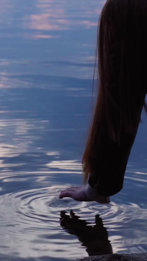 Close-up of a woman's hand gently touching the water on the shore of the lake. Stock Footage 273672656