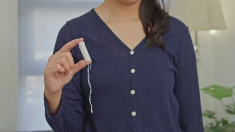 Close-up of woman's hand holding clean white cotton tampon with string for Stock Footage 340575809