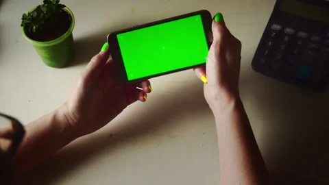 Close-up of a woman's hand holding a mobile phone with a vertical green screen. Stock Footage 181529621