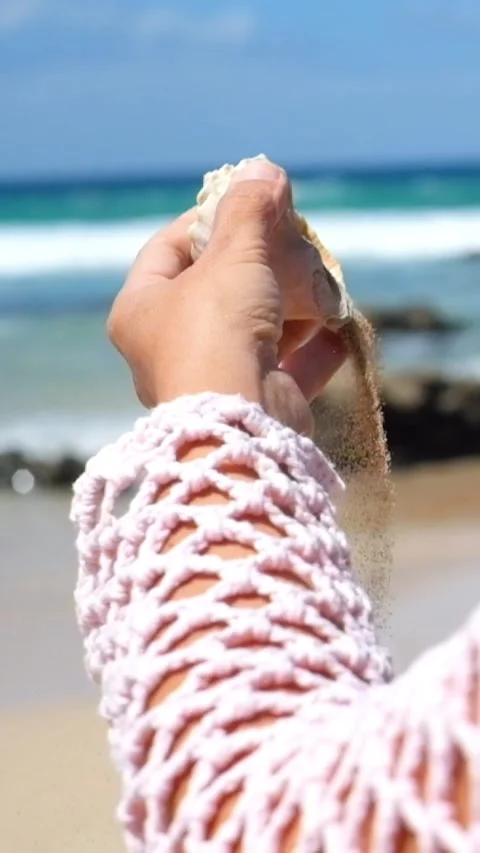 Close-up of a woman's hand holding a seashell and pouring fine sand from it Vídeo Stock 344848007