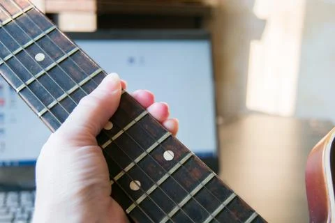 Close-up of a woman's hand holding the strings of an acoustic guitar. Online  Stock Photos