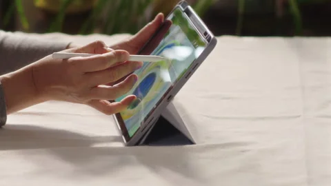 Close-up, womans hand holding tablet on table and drawing peacock feather on Stock Footage 315368257