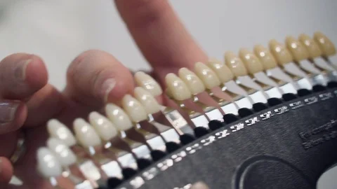 Close-up of a woman's hand holding a tooth color scale. Shade selection of teeth Stock Footage 75403744