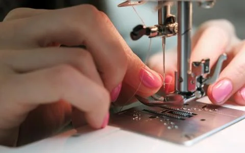 Close-up of the woman's hand is inserted into the needle thread sewing machine. Foto stock
