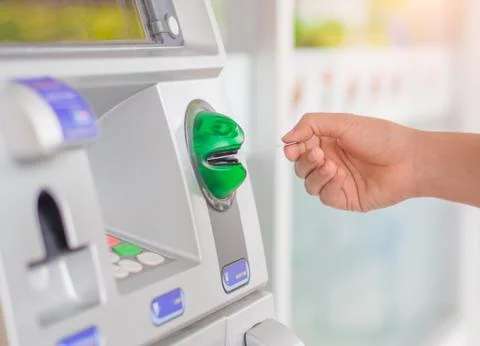 Close-up of woman's hand inserting debit card into an ATM machine. Stock Photos