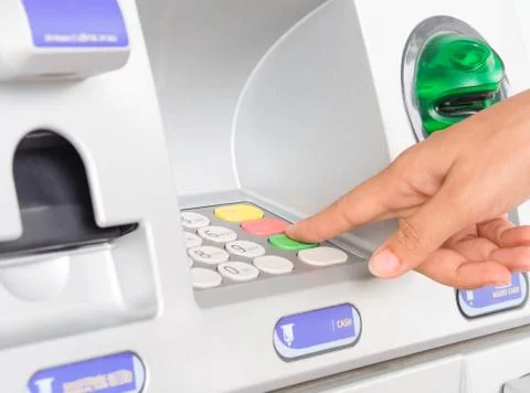 Close-up of woman's hand inserting debit card into an ATM machine. Stock Photos