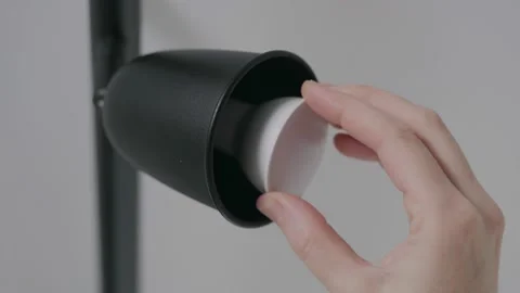Close-up of a woman's hand inserting an led light bulb into the ceiling of a Stock Footage 146977549