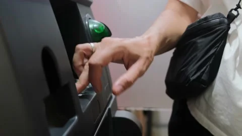 Close-up of a woman's hand inserts a plastic card into an ATM and enters a pin Stock Footage 220504438