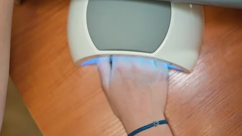 Close-up of a woman's hand in a lamp for drying manicure Stock Footage 338447142