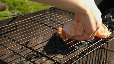 Close-up of a woman's hand laying out a chicken on a grill for frying. Stock Footage 200789739
