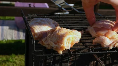 Close-up of a woman's hand laying out a chicken on a grill for frying. Stock Footage 200789800