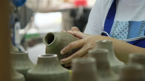 Close-up of a woman's hand making patterns on a clay vase in a pottery workshop. Stock Footage 194532397